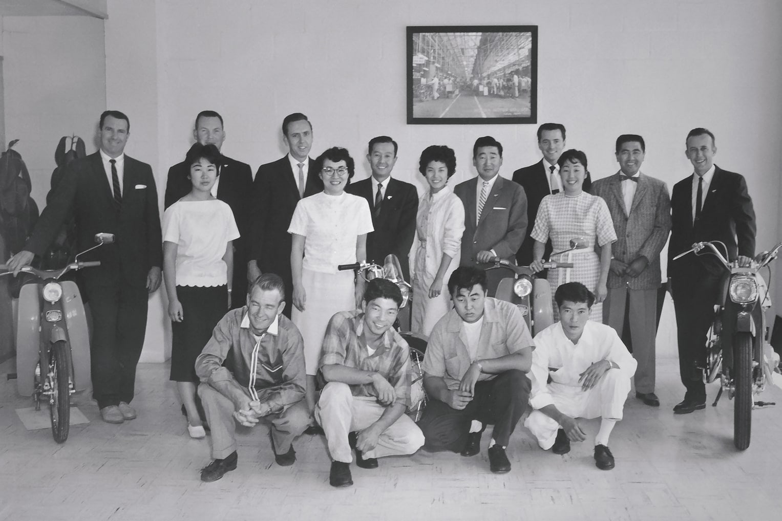 Honda employees posing for a photo with classic Honda motorcycles.
